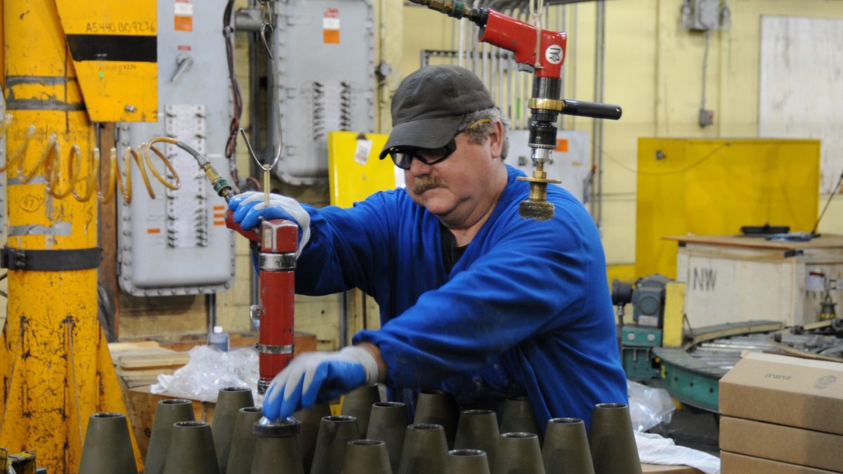 A contractor performs load, assemble and pack operations on 155mm artillery rounds at the Iowa Army Ammunition Plant production line.