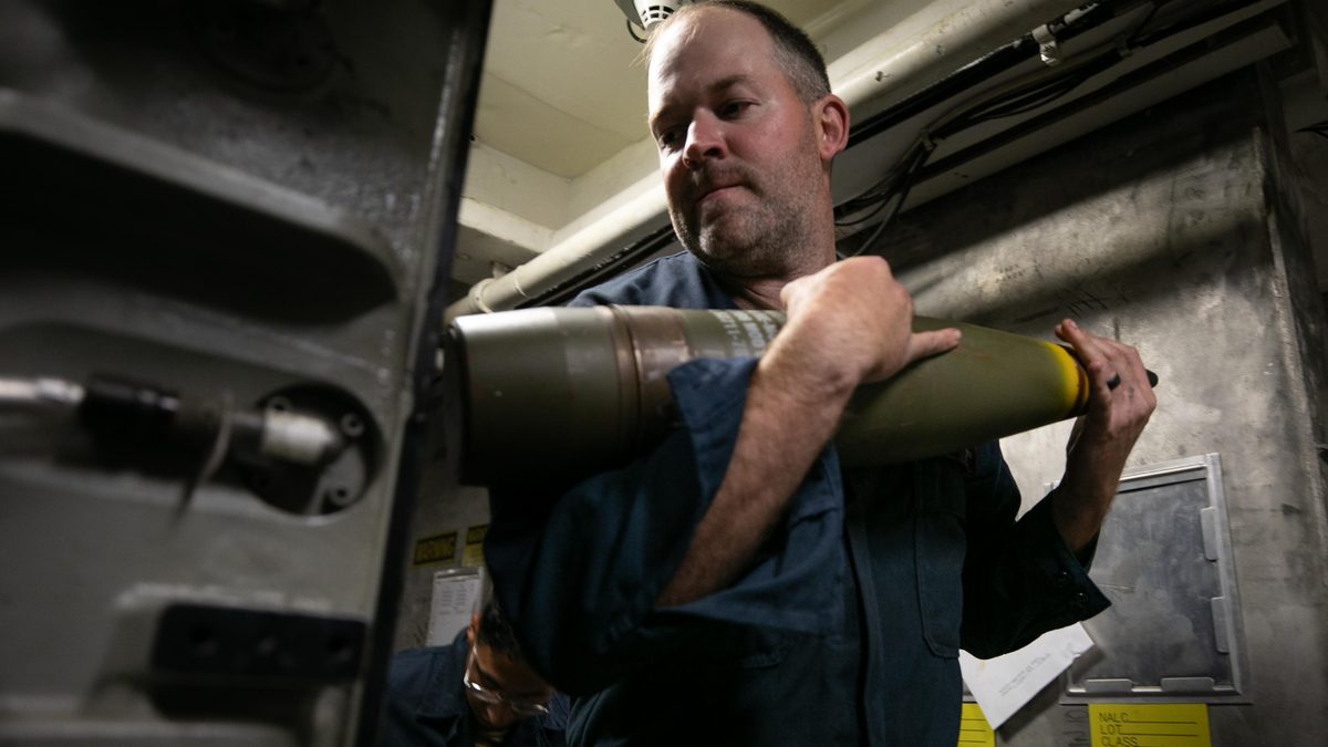 US Navy Gunner's Mate loads 5-inch projectiles from the deep magazine room aboard USS Arleigh Burke